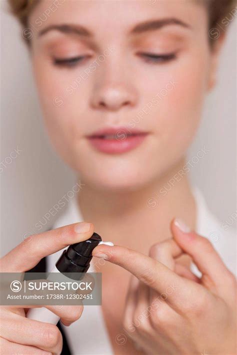 Woman Squirting Moisturizer On Her Finger Superstock