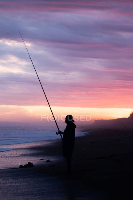 Silhouette Of A Man Fishing On The Seashore At Sunset — Men Landscape