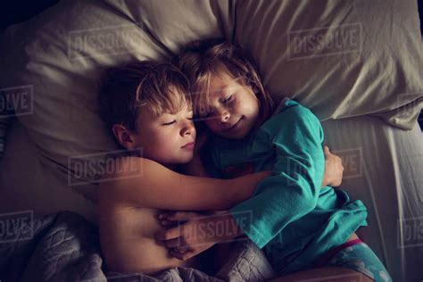 Overhead View Of Loving Siblings Sleeping Together On Bed At Home