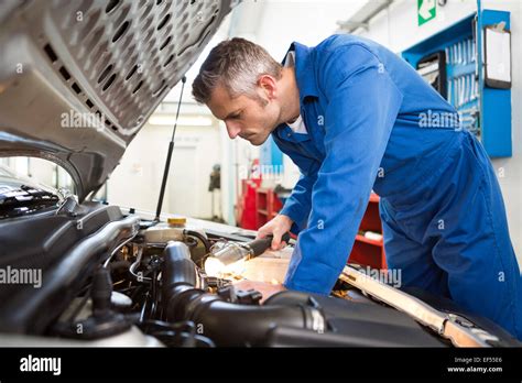 Mechanic Examining Under Hood Of Car With Torch Stock Photo Alamy