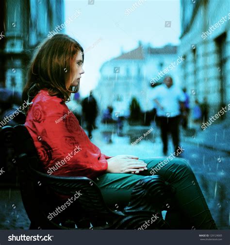 Beautiful Sad Girl Sitting In The Rain On The Street Of