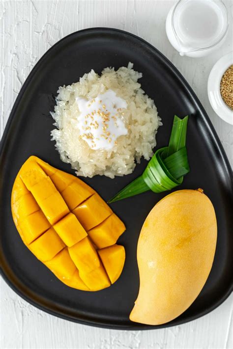 A Black Plate Topped With Mangoes Rice And Other Food On Top Of A