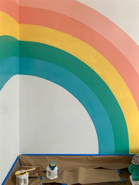 There Is A Rainbow Painted On The Wall In This Room With Paint Rollers