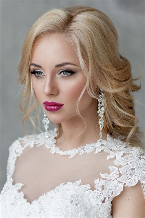 A Woman With Blonde Hair Wearing A Wedding Dress And Earrings Posing