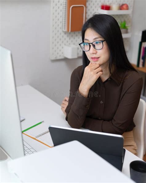 female office worker considering about her work at office desk in office room stock image