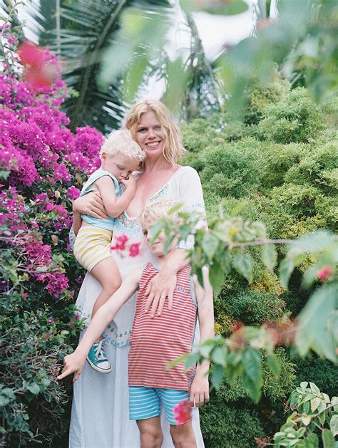 Pretty Blonde Mom And Two Sons In Striped Pajamas Standing In Garden On Film By Stocksy