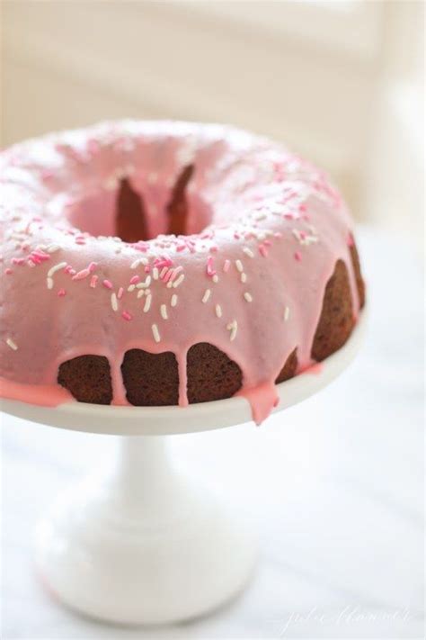 A Bundt Cake With Pink Icing And Sprinkles On A Plate