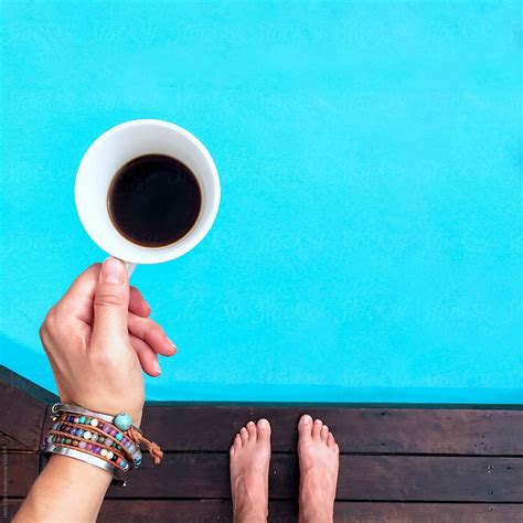 Overhead View Of Woman S Hand Holding Cup Of Coffee While Standing Next To Pool By Stocksy