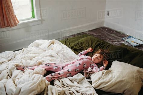 Young Girl Laying On Bed Wearing Pjs In Freshly Painted Bedroom Stock