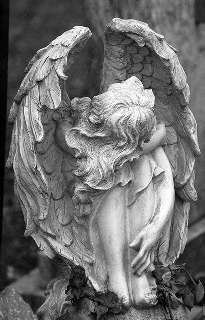 An Angel Statue Sitting On Top Of A Grave