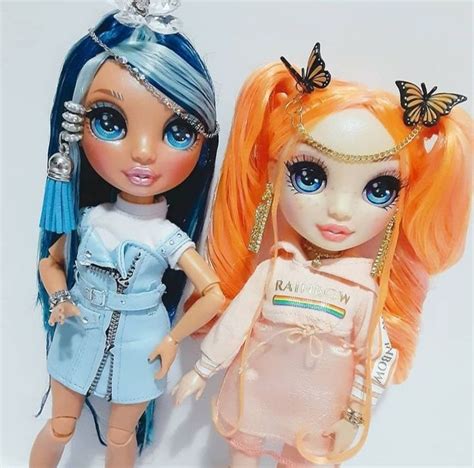 Two Dolls Are Standing Next To Each Other On A White Surface One Has