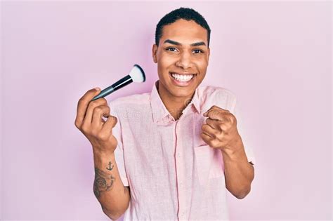 Young African American Guy Holding Makeup Brush Screaming Proud
