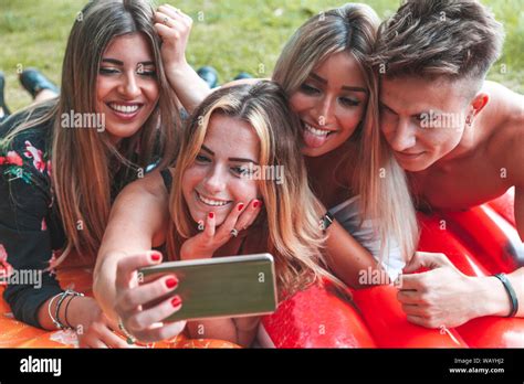 Group Of Millennial Friends Taking A Selfie Outdoors Lying In The Grass