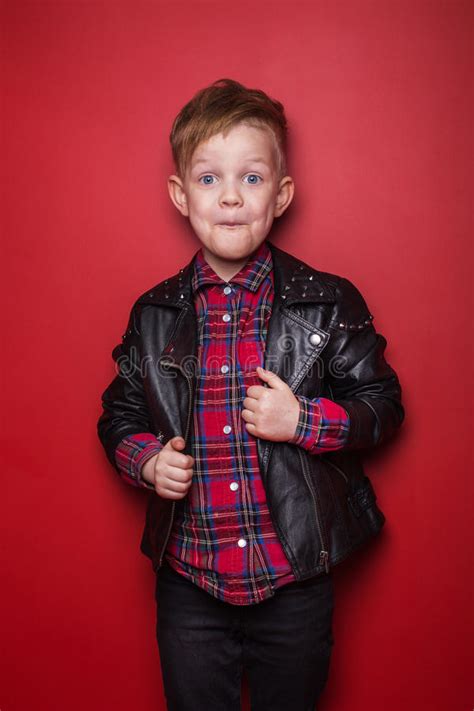 Fashion Little Boy Wearing A Leather Jacket Studio Portrait Over Red