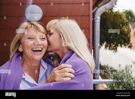 Blond Woman Kissing Mother On Cheek Standing In Balcony Stock Photo Alamy