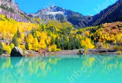 Bright Turquoise Blue Lake With Yellow Fall Foliage And Mountain Peak