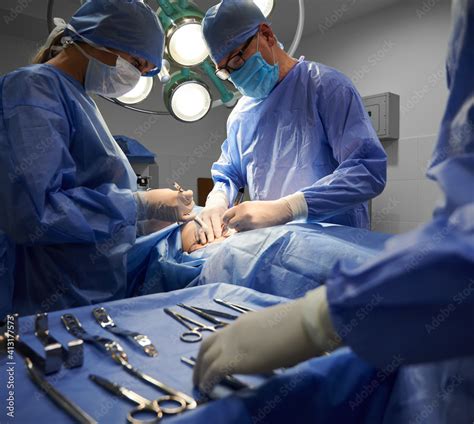 Foto De Medical Team In Surgical Suits Performing Aesthetic Surgery In