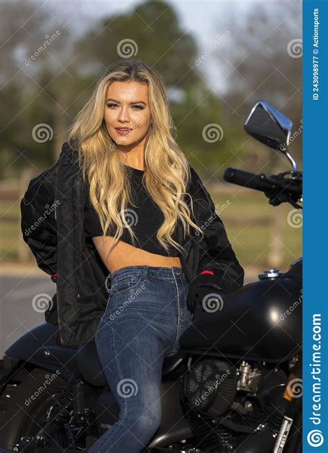 A Lovely Blonde Model Enjoys The Outdoor Weather While Posing With Her Motorcycle Stock Image