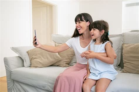 Free Photo Happy Excited Mom And Little Daughter Using Phone For Video Call While Sitting On