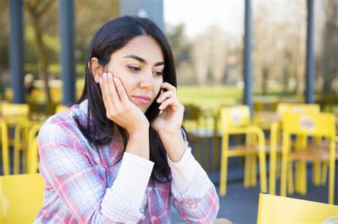 Mulher séria falando no celular no café ao ar livre Foto Grátis