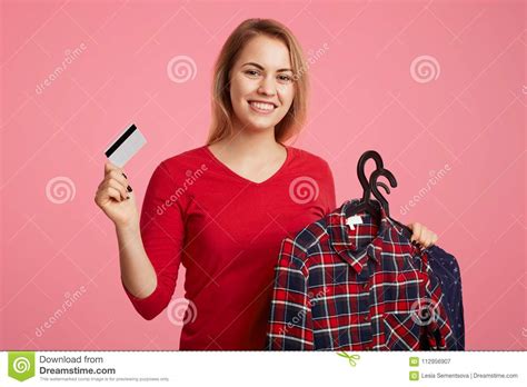 Helping our customers meet their financial needs is important to us. Portrait Of Positive Glad Female Model Holds New Clothing ...