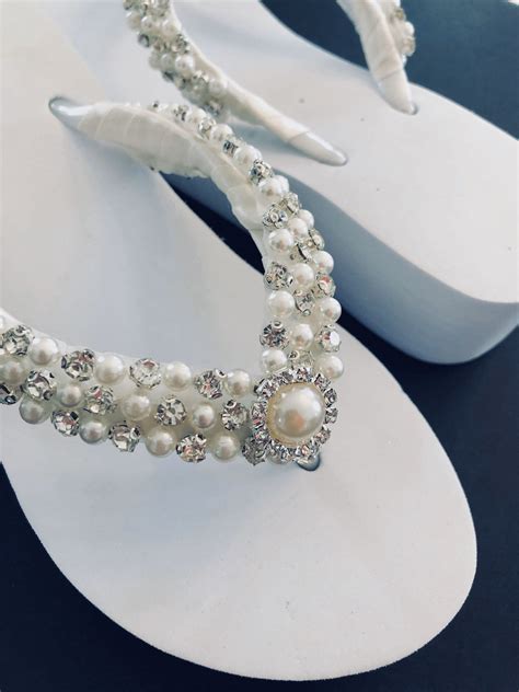 A Pair Of White Sandals With Pearls On Them