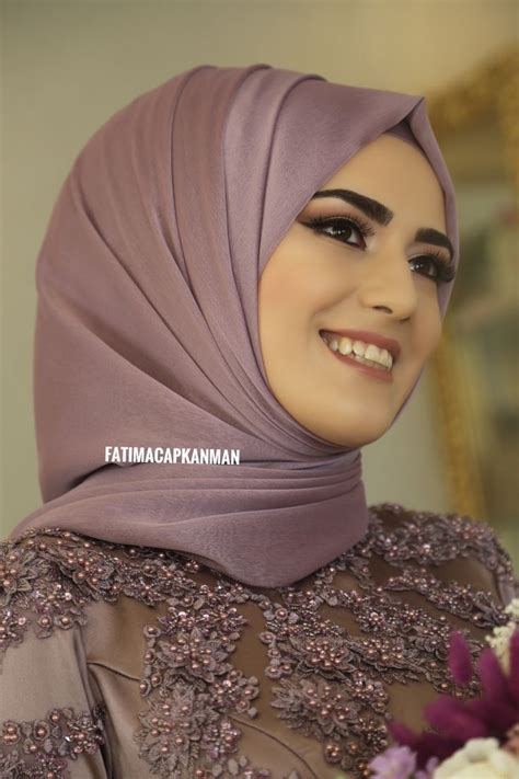 A Woman Wearing A Purple Hijab Smiles At The Camera While Holding A