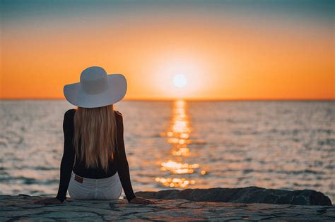 Woman Sitting On A Rocky Shore By The Sea And Watching Sunset Free Stock Photo Picjumbo