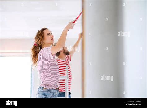 Beautiful Young Couple Painting Walls In Their New House Using Paint