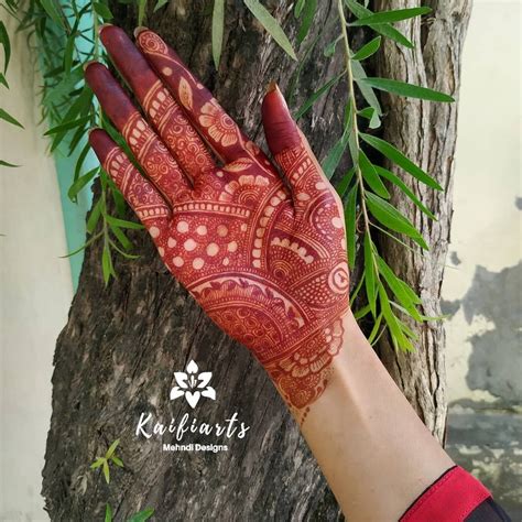 A Womans Hand With Henna On It And Green Leaves In The Background