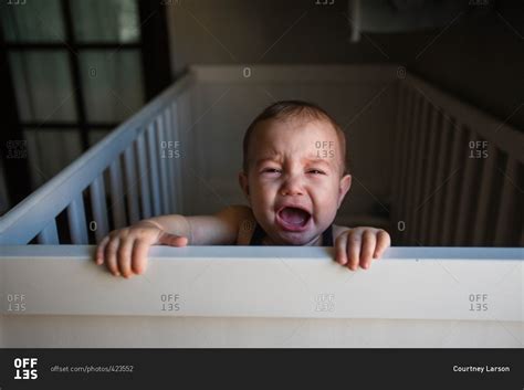Baby Crying While Holding Onto Edge Of Crib Stock Photo Offset