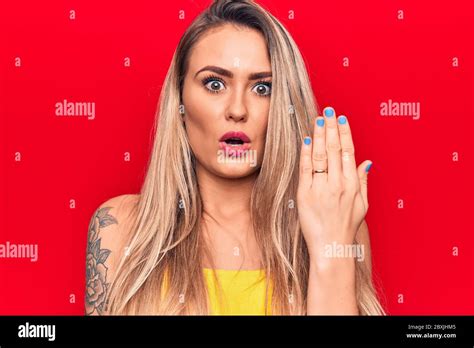 Young Beautiful Blonde Woman Showing Engagement Ring Over Isolated Red Background Scared And