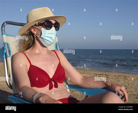 Woman In Red Bikini Sunglasses And Hat Wearing Surgical Face Mask At