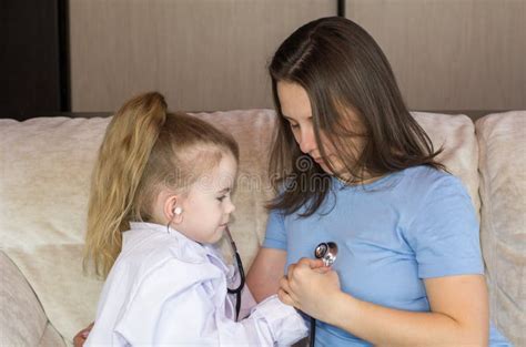 Little Girl Dressed In Medical Uniform Playing As Doctor With Mom Stock
