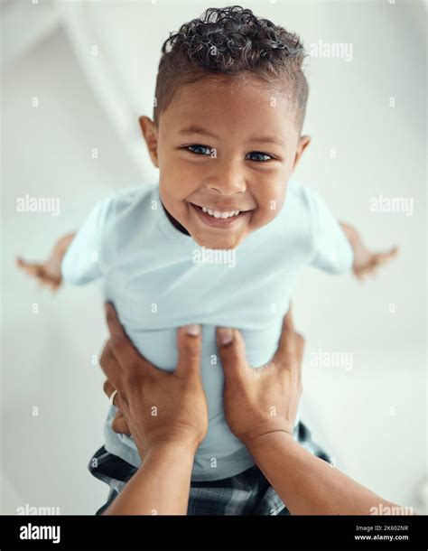 Happy Little Mixed Race Boy Lying In Fathers Arms While Looking At The