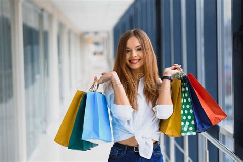 Beautiful Girl With Shopping Bags Is Looking At Camera And Smiling While Doing Shopping In The