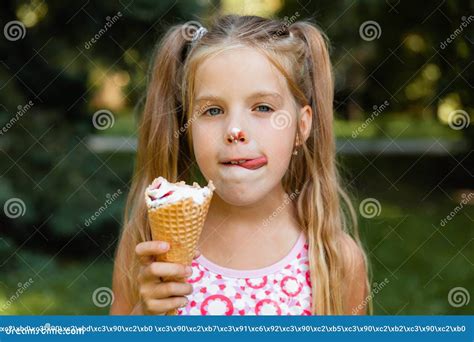 beautiful little blonde girl eating ice cream in the summer in the park cheerful girl with ice