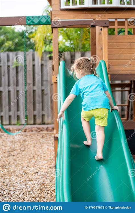 Child Climbing Sliding And Playing On Green Slide On Outdoor Play Set