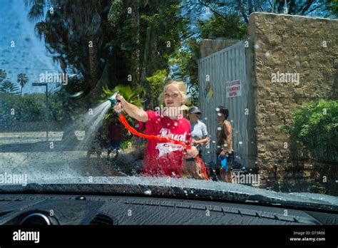 A female teenage student uses a hoses to rinse off a car at a high