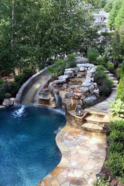 An Outdoor Swimming Pool With Waterfall And Rock Steps Leading Up To