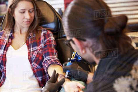 Woman Sitting In Chair Having Tattoo On Arm In Parlor Stock Photo Dissolve