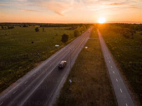 Aerial View Of A Car Driving On A Road At Sunset In Countryside Stock