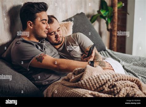 Happy Gay Couple Lying Together In Bed And Using Smartphone Looking At Photos Stock Photo Alamy