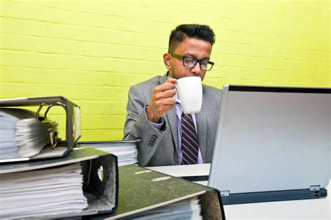 Portrait Of Indian Businessman Holding Mug And Working On His Laptop