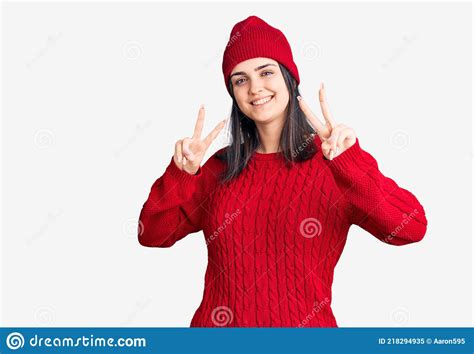 Young Beautiful Girl Wearing Sweater And Wool Cap Smiling Looking To