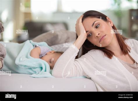 Tired Mother Sleeping Beside Her Sleepy Daughter On A Bed Stock Photo