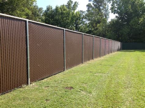 A Large Brown Fence In The Middle Of A Grassy Area Next To Trees And Bushes