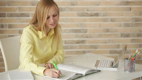 Pretty Girl Sitting At Desk Studying Writing In Notebook Using Laptop