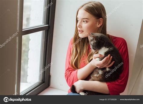 Young Woman Holding Cute Cat While Looking Window — Stock Photo