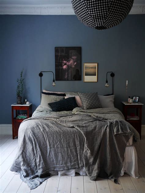 Front view of stylish loft bedroom with gray and white walls, dark wooden floor, comfortable king size bed, round bedside table and shelves in background. 10x Blauw in interieur | HOMEASE | Blue bedroom walls ...